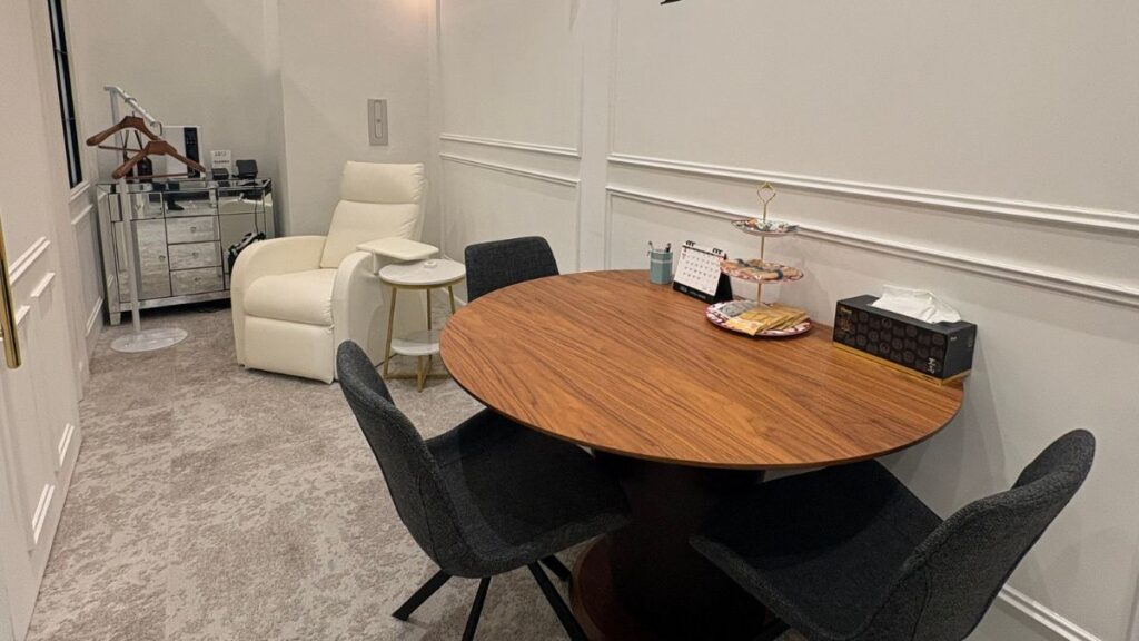A luxury consultation room with a round wooden table and neutral decor.