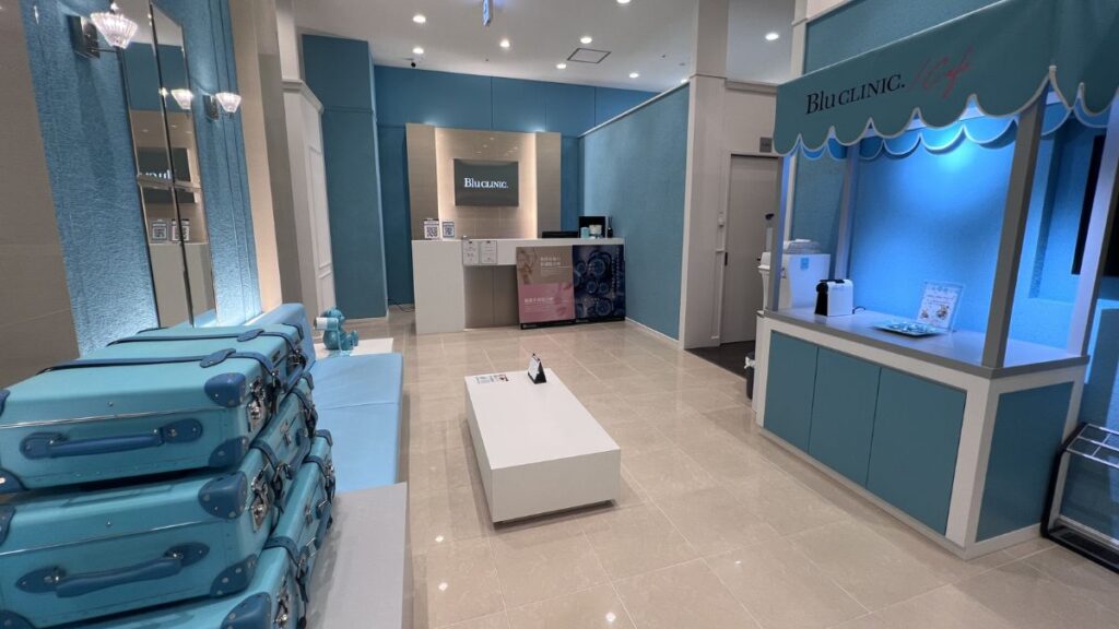 Modern reception and lounge area of BLU CLINIC, featuring light blue and white interior decor, a front counter, and blue trunk-styled seating.