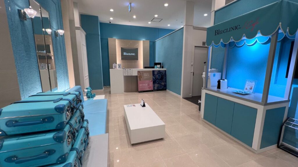 Modern clinic reception area decorated in bright light blue and white with a Blu CLINIC logo sign.